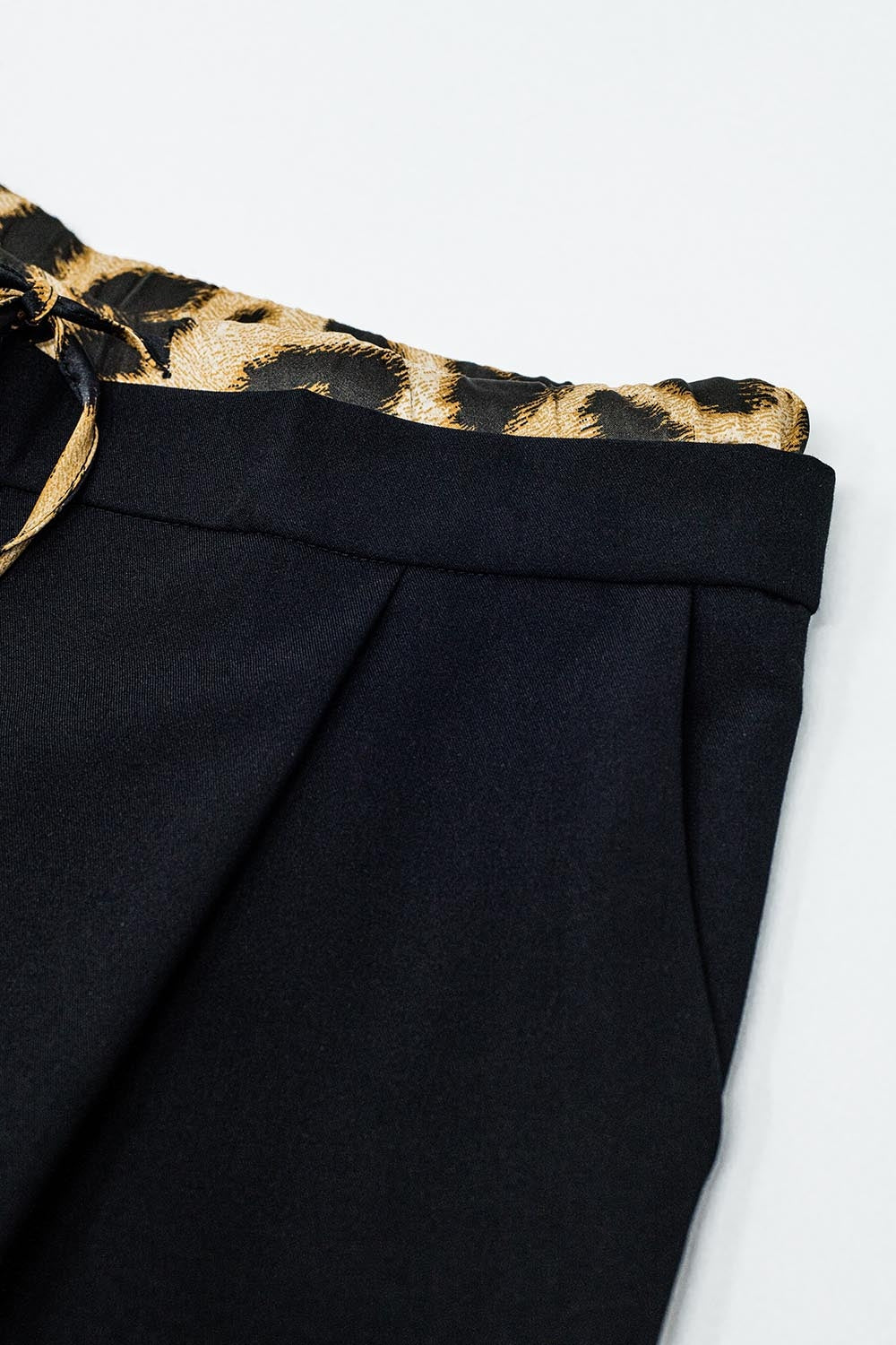 Long black pleated pants with leopard detail at the waist